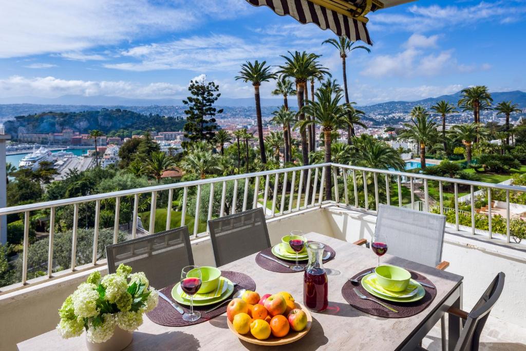 una mesa con un bol de fruta en el balcón en Ferienwohnung Les Oliviers über den Dächern von Nizza ruhig sonnig Meerblick Pool Tiefgarage Parkplatz, en Niza