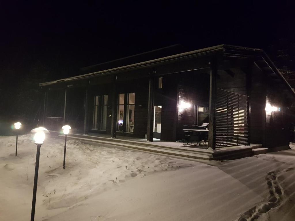 un petit bâtiment avec des lumières dans la neige la nuit dans l'établissement Villa Vilmala, à Sääskilahti