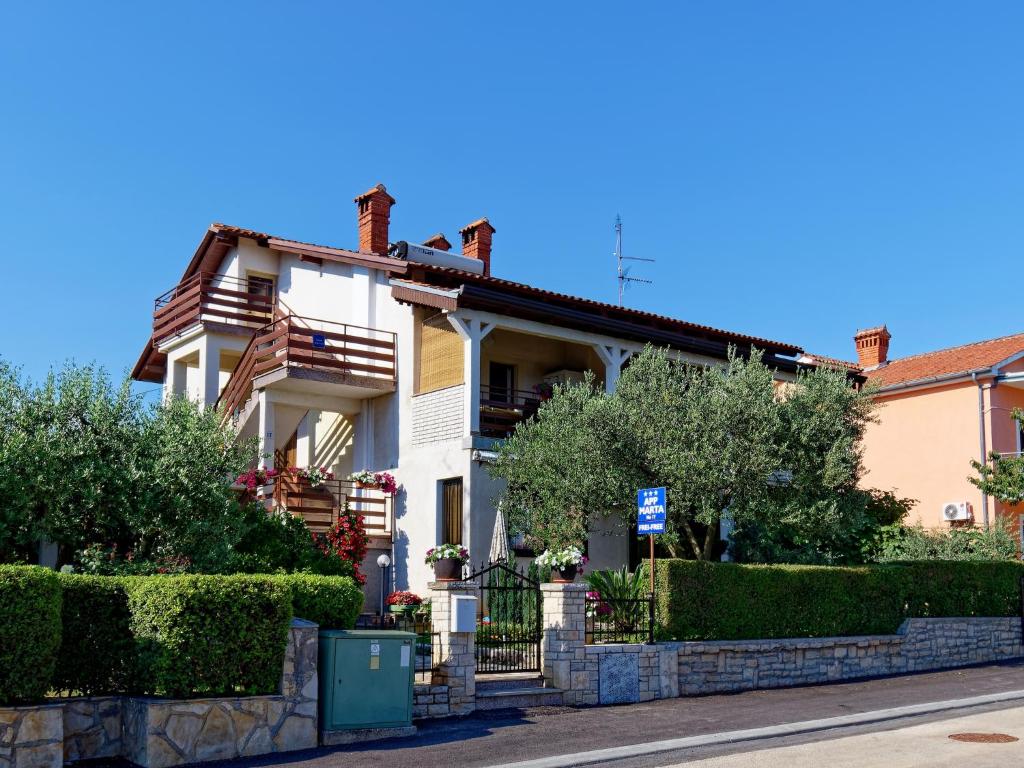 ein weißes Haus mit einem Zaun und Büschen in der Unterkunft Apartments Marta in Novigrad Istria