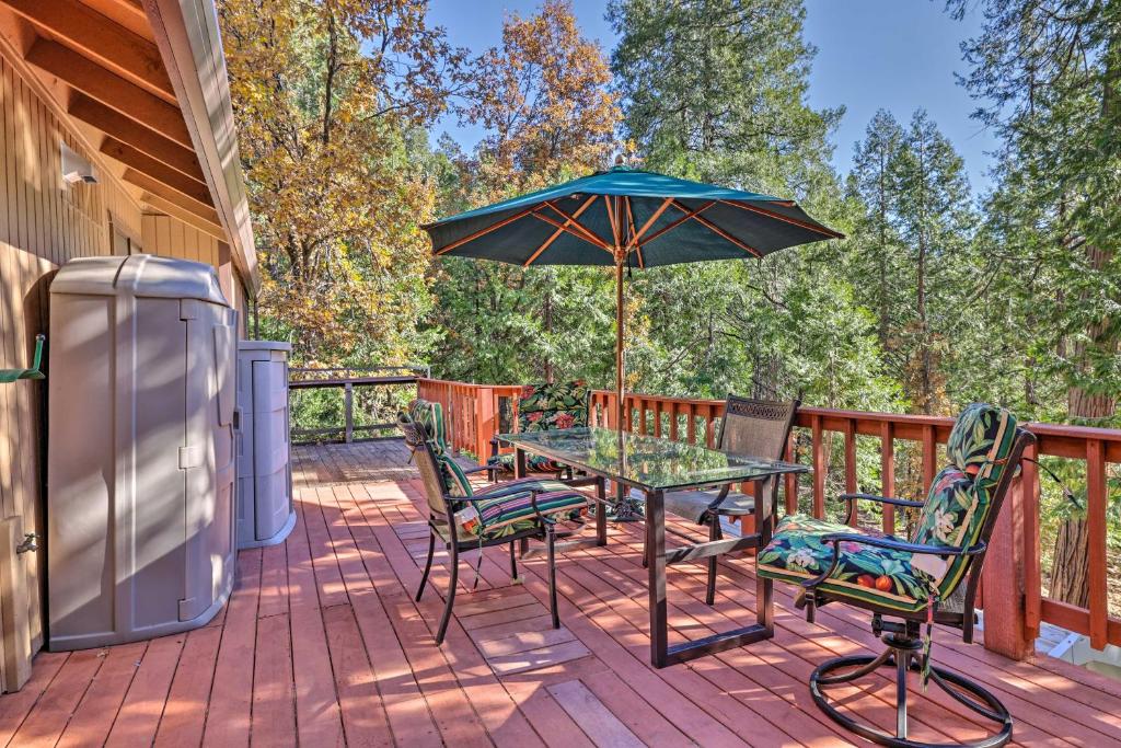 a patio with a table and chairs and an umbrella at Quiet and Cozy Twain Harte Cabin with Forest View in Twain Harte