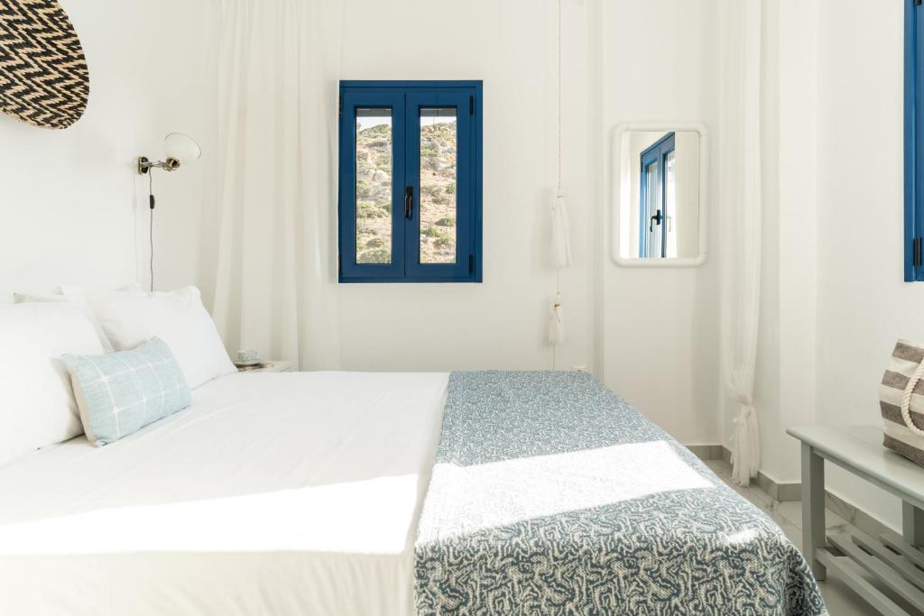 a white bedroom with a bed with a blue window at Alasthas in Gavrio