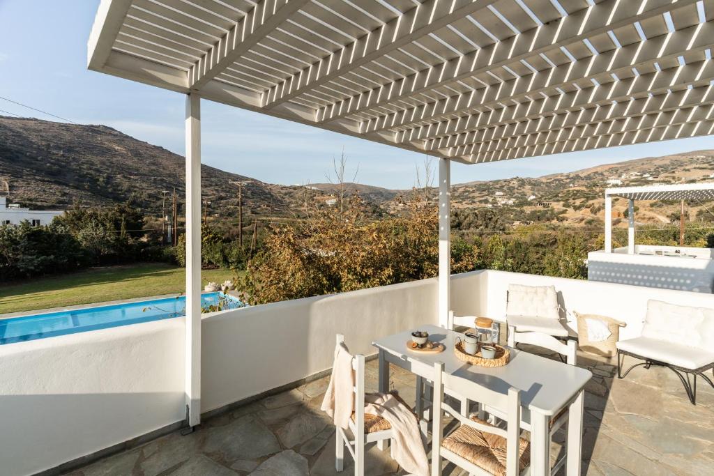 a white pergola on a patio with a table and chairs at Alasthas in Gavrio