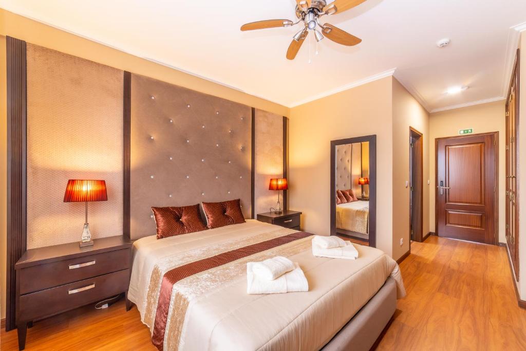 a bedroom with a large bed and a ceiling fan at Boa Vida Alojamentos in Vagos