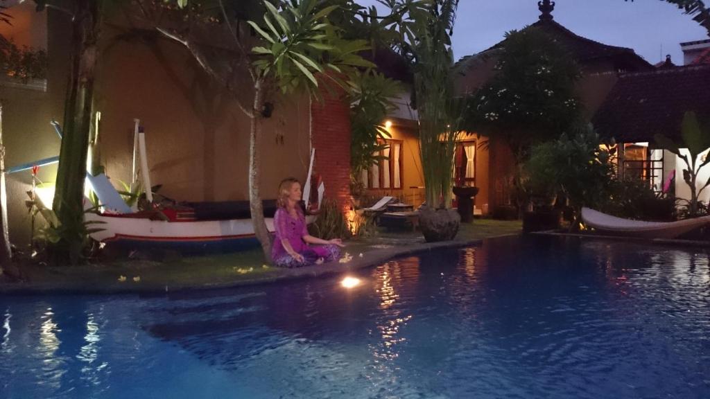 Praschita Bali في سانور: فتاة صغيرة جالسة بجوار حمام السباحة