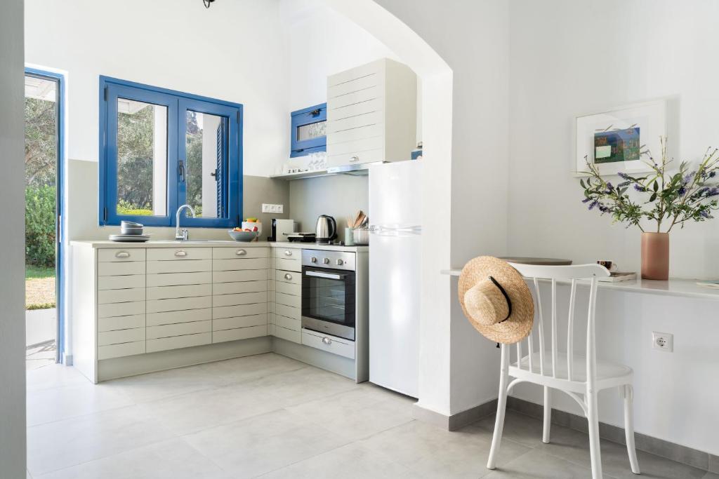 a kitchen with white cabinets and a table and a chair at Alasthas in Gavrio