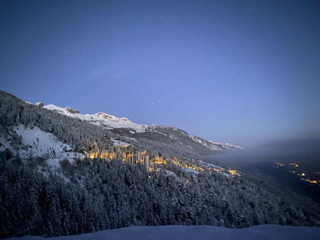 a view of a mountain with a city at night at Résidences Kandahar in Crans-Montana