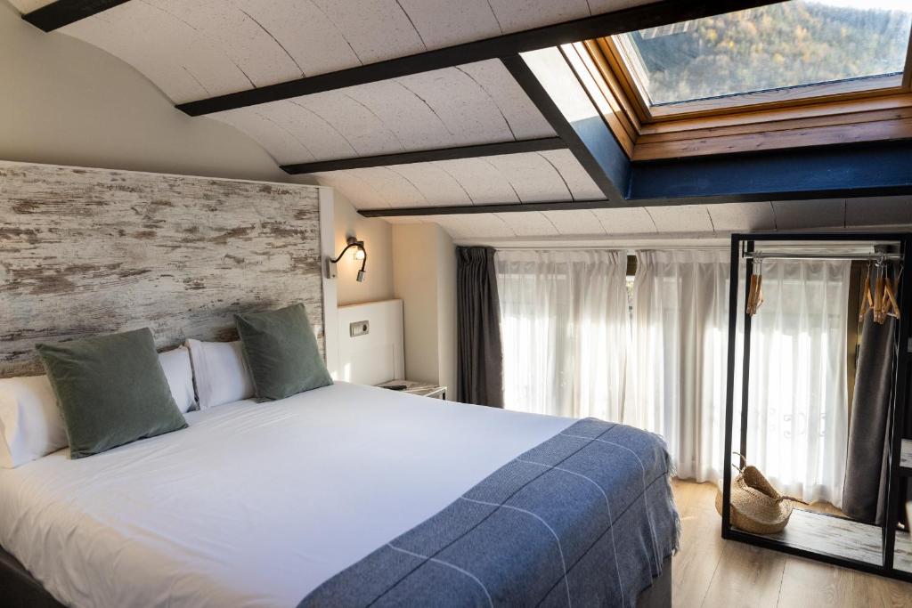 Un dormitorio con una cama grande y una ventana en Hotel Cims de Camprodon en Camprodon