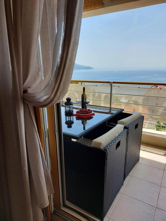 uma varanda com uma mesa e vista para o oceano em Apartment-Hotel Vila Petrovic-Becici em Budva