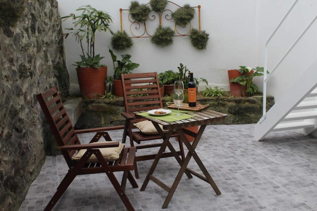 una mesa con 2 sillas y una copa de vino en Casa Amarela AL 3030, en Horta
