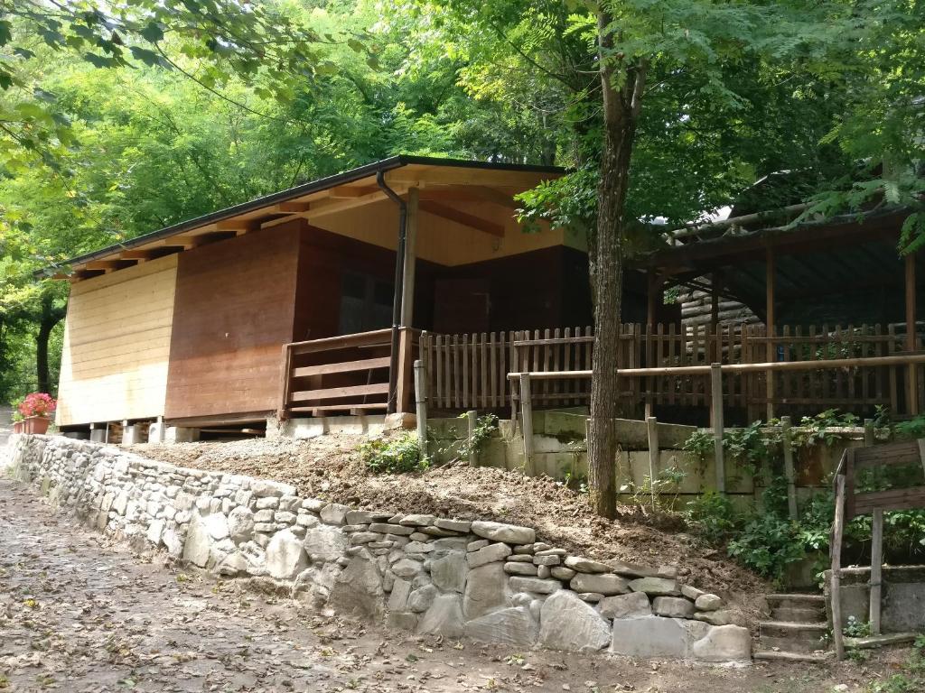 a log cabin with a stone wall in front of it at Le sorgenti - Chalet 42 in Palazzuolo sul Senio