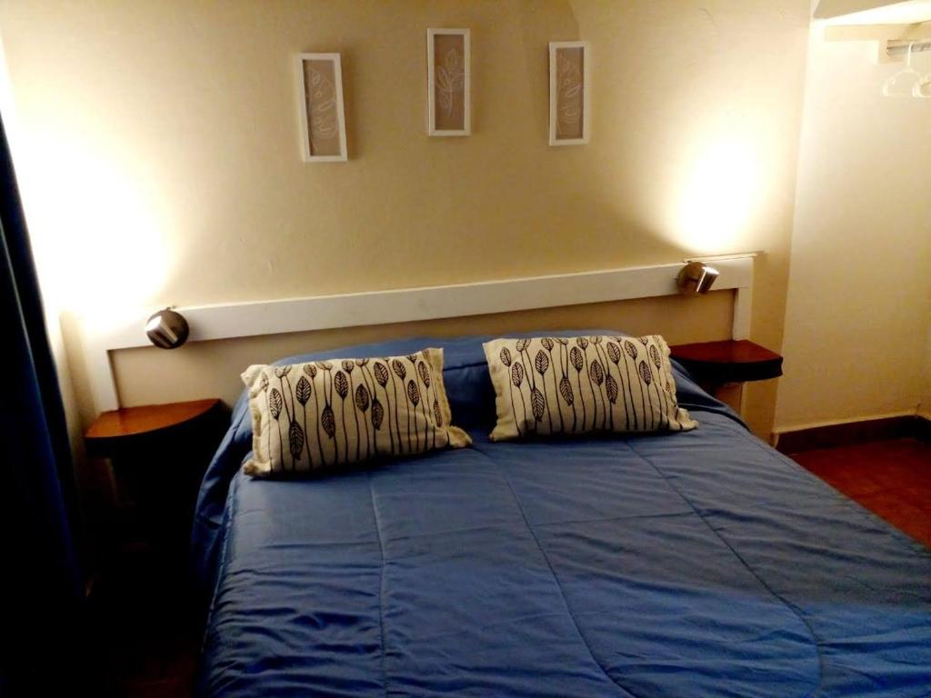 1 dormitorio con 1 cama azul y 2 almohadas en Dulcich Alojamiento en Merlo