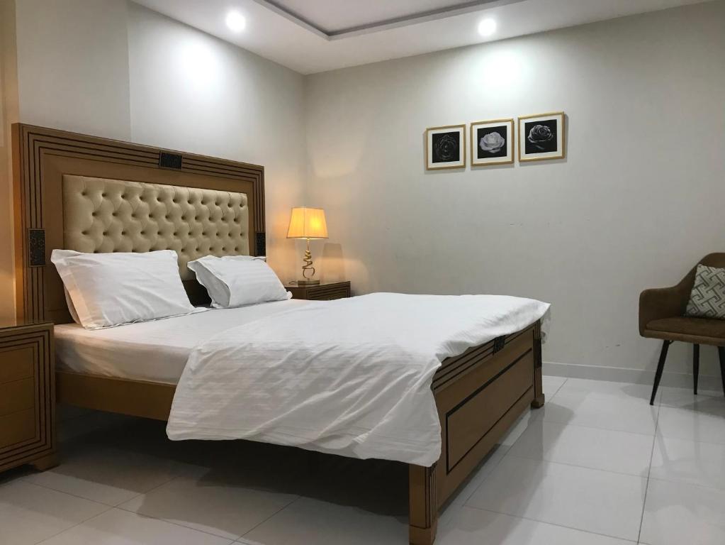 a bedroom with a large bed and a chair at Mukhtar Homes Bahria Town Lahore in Lahore