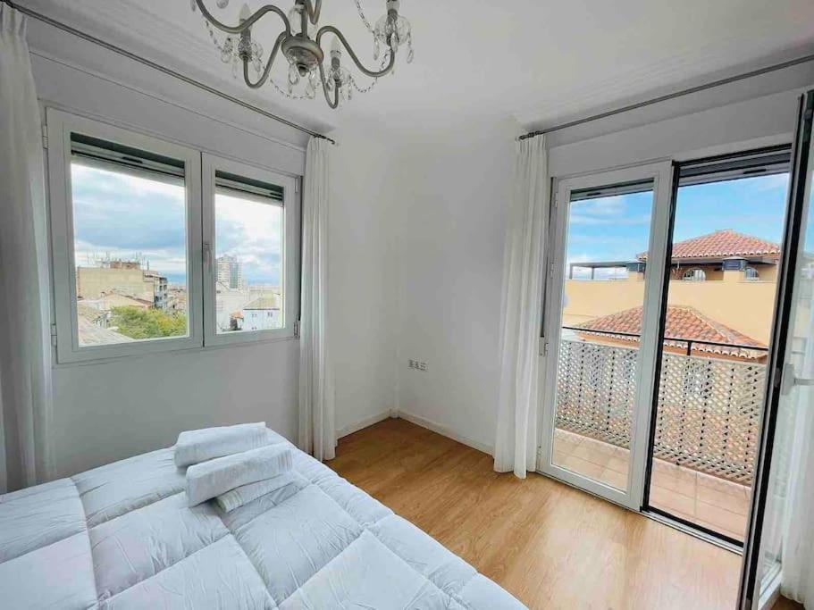 a white bedroom with a bed and large windows at Apartamento centro de Granada 2 in Granada