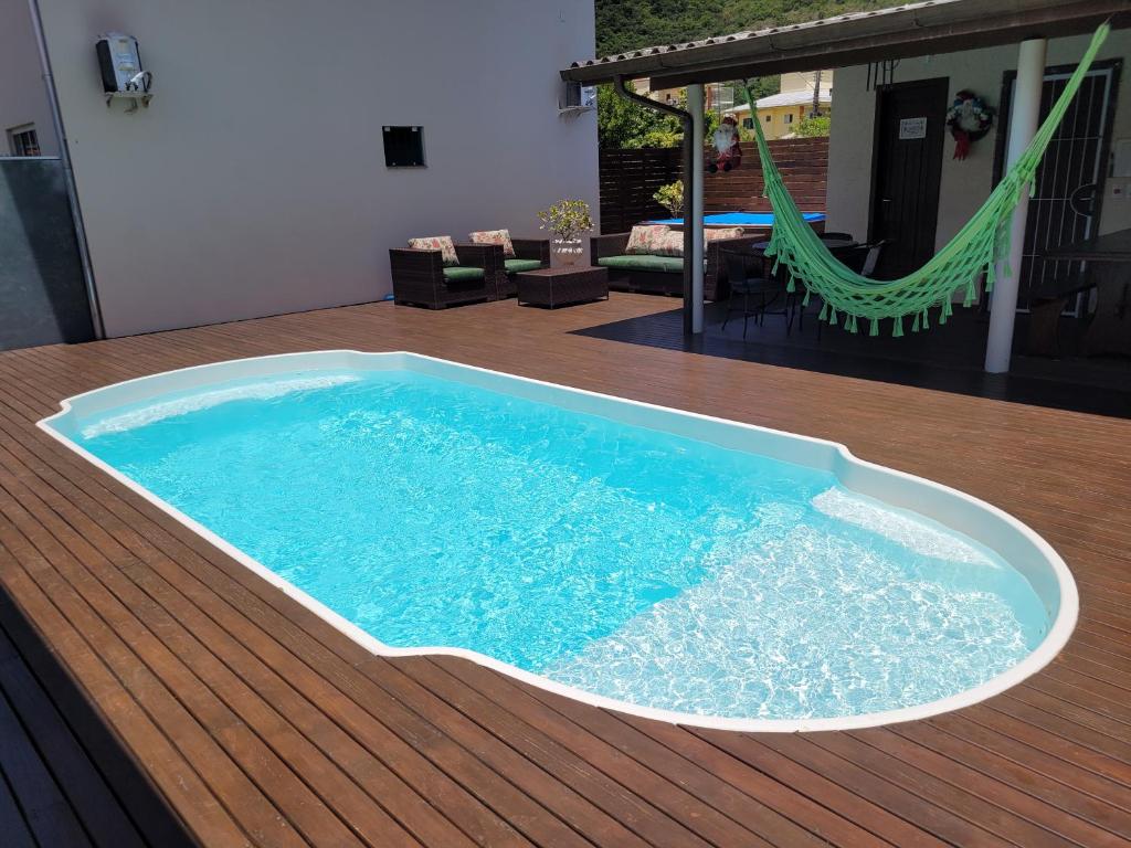 a swimming pool on a deck with a hammock at Aptos do Angelo in Pinheira