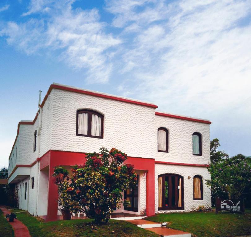 uma casa branca e vermelha com uma árvore em frente em Hotel La Casona em La Paloma