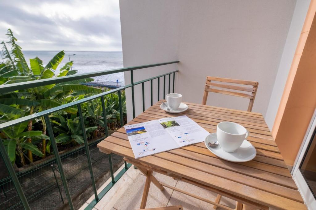 un tavolo di legno su un balcone con vista sull'oceano di Sol&mar a Ponta do Sol