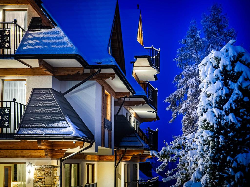 a snow covered christmas tree next to a building at Villa Taternik by Golden Apartments in Zakopane
