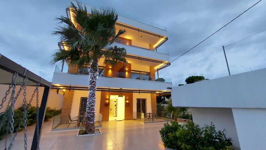 a house with a palm tree in front of it at FINIKAS Suites & Apartments 10min from Athens Airport in Artemida