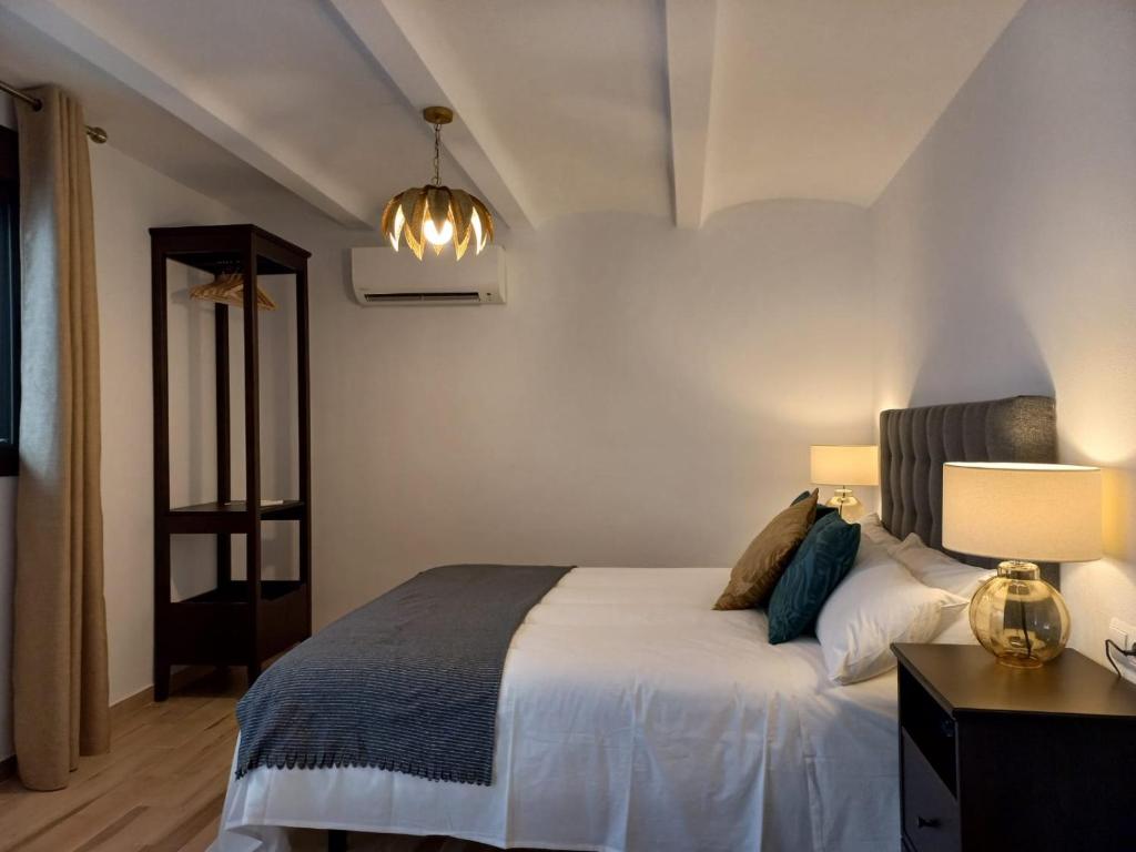 CASA RURAL ÁGUILAS HOME zhr في زاهارا دي لا سييرا: غرفة نوم بسرير وطاولة بها مصباحين