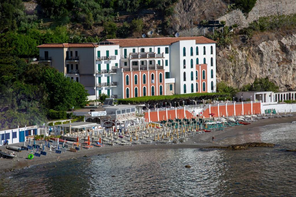 a large building with chairs and umbrellas on a beach at Hotel Lido Mediterranee in Taormina