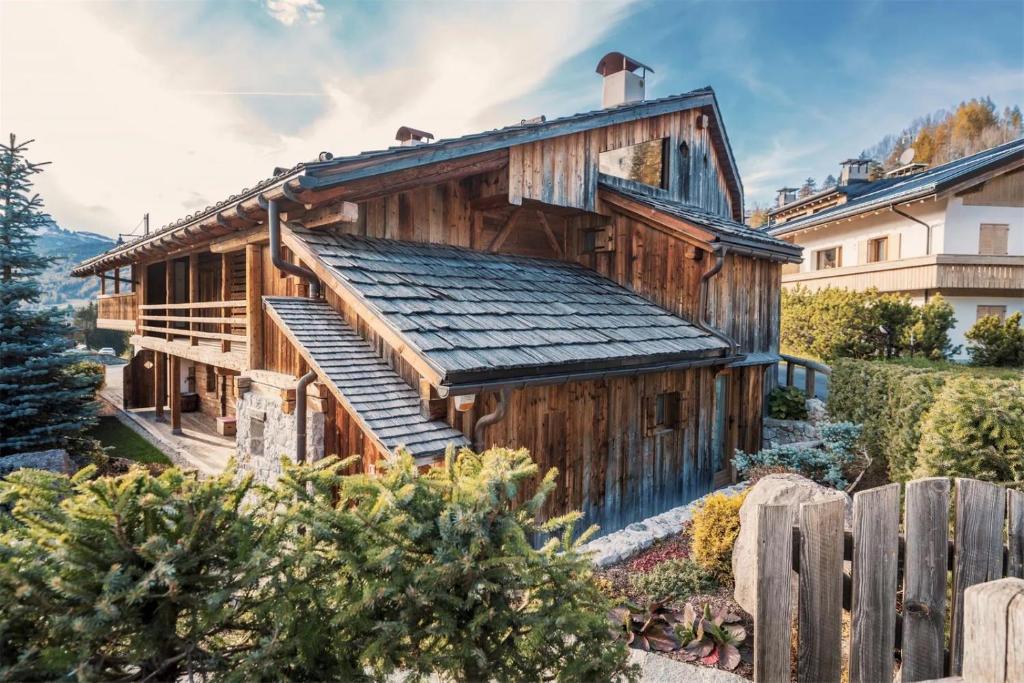 a wooden house with a porch and a fence at Luxury Cortina in Cortina dʼAmpezzo
