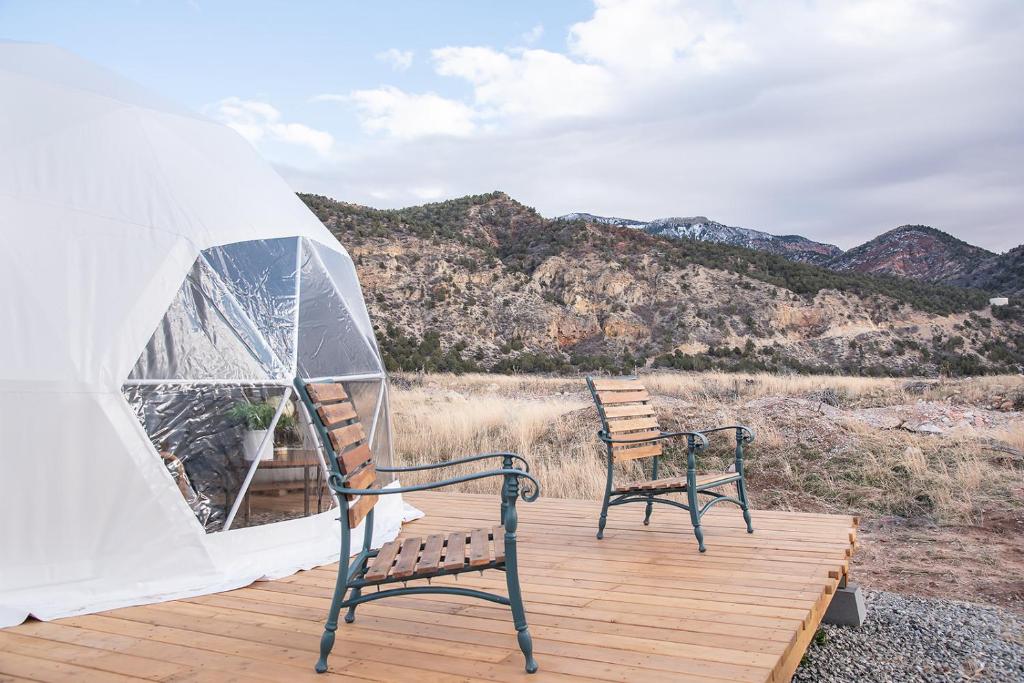 two chairs sitting on a wooden deck next to a tent at Little Village Retreat in New Harmony