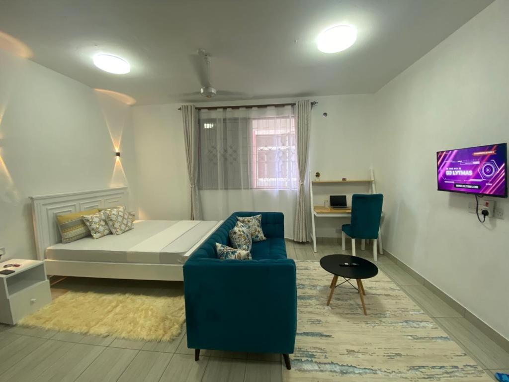 een kamer met een bed, een bank en een tv bij The Chillspot in Mombasa