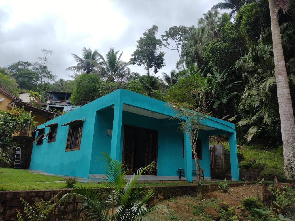 a blue house in a yard with trees at Recanto das Palmeiras Praia da Longa in Angra dos Reis