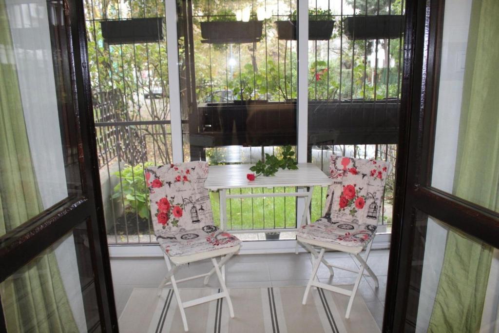 a porch with two chairs and a table and windows at N&AA apartman in Belgrade