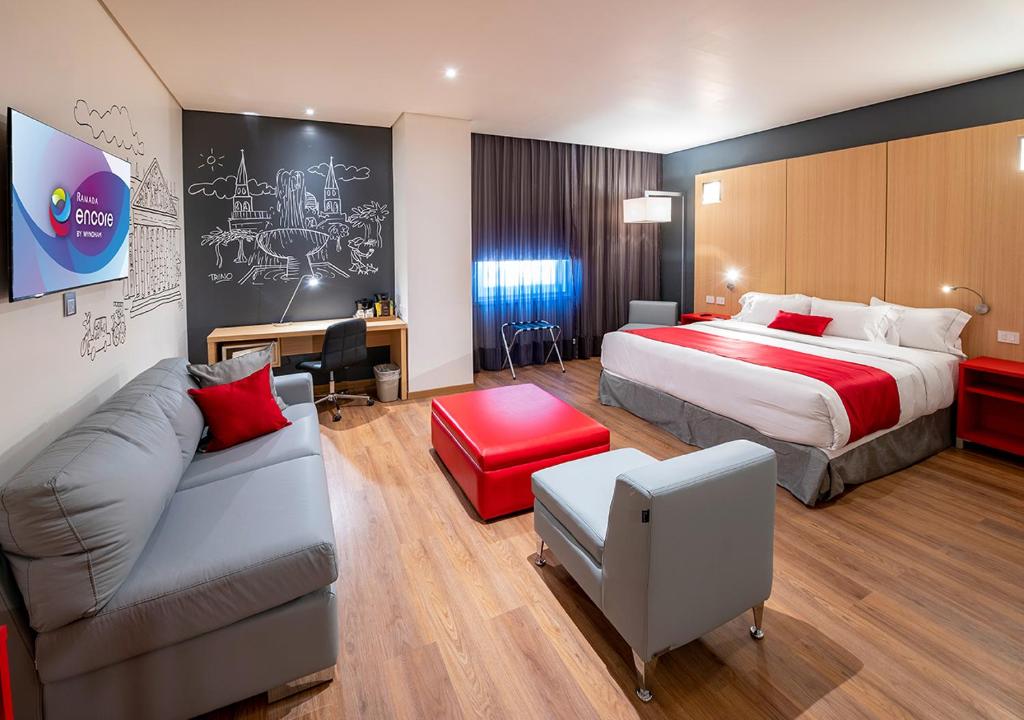 a hotel room with a bed and a couch at Ramada Encore by Wyndham Guadalajara Aeropuerto in Guadalajara