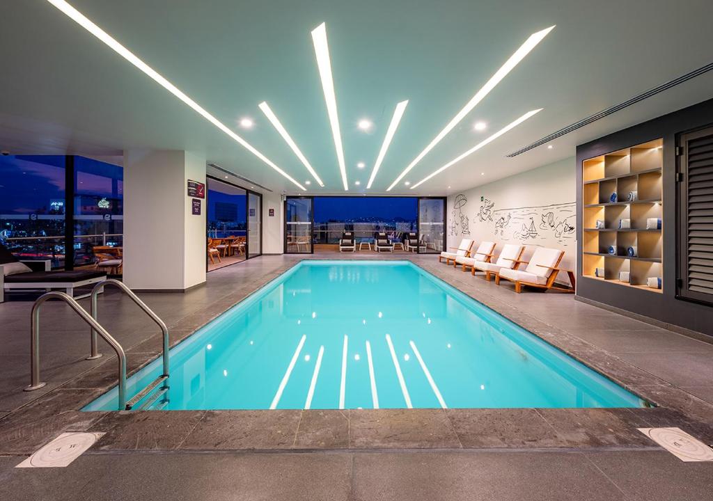 a swimming pool in a building with a restaurant at Ramada Encore by Wyndham Guadalajara Aeropuerto in Guadalajara