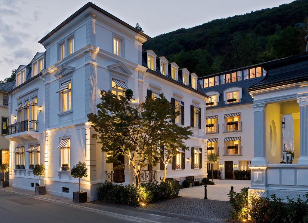 un grand bâtiment blanc avec un arbre en face dans l'établissement House of Hütter - Heidelberg Suites & Spa, à Heidelberg