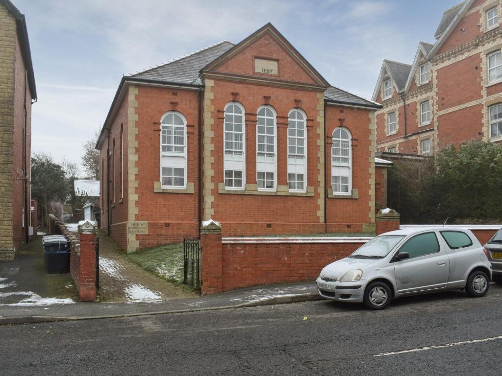 a silver car parked in front of a brick building at The Old Quaker House Apartment in Llandrindod Wells