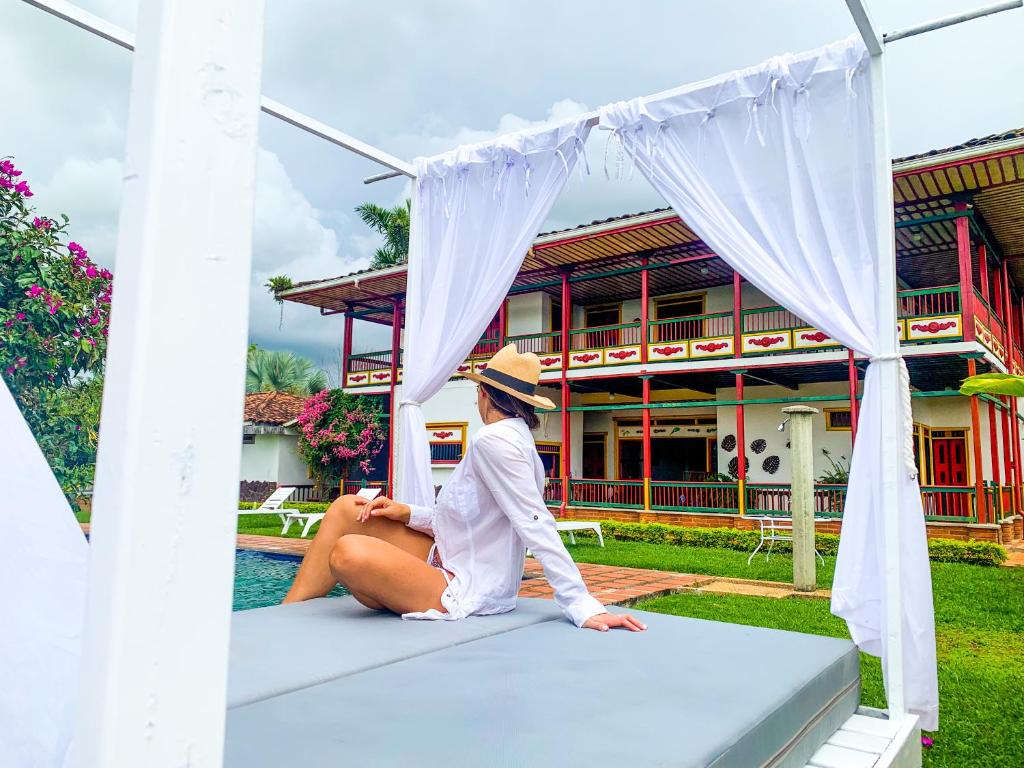 a woman sitting on a bed in front of a house at Finca El Descanso del Duque in La Palmilla