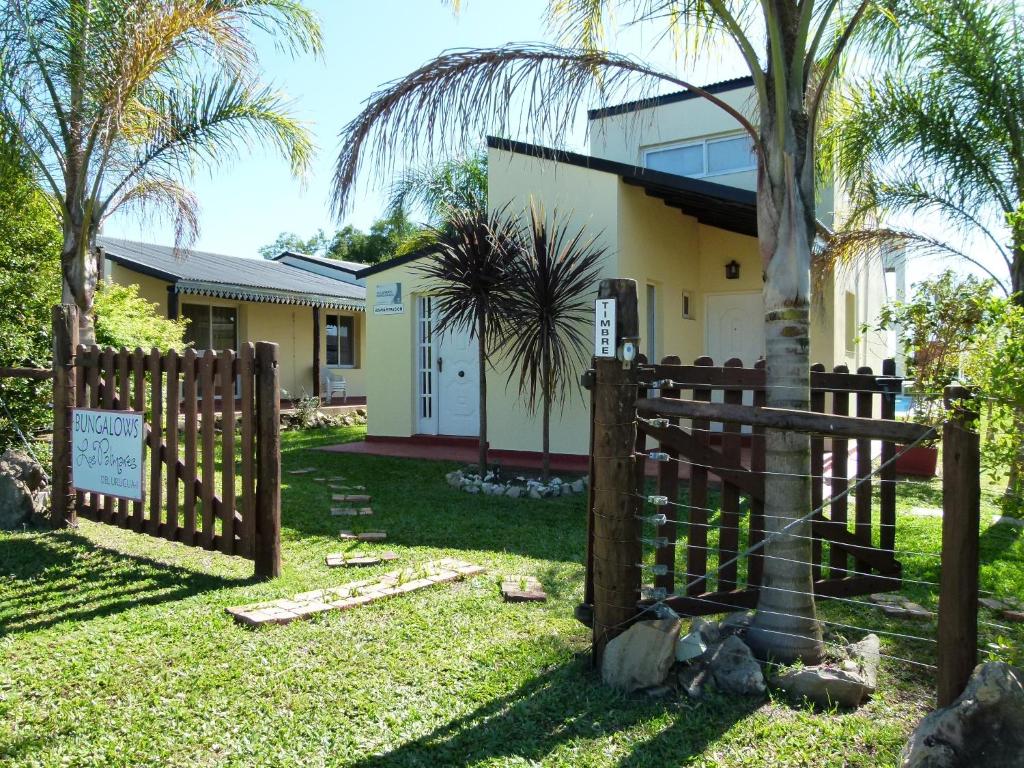 a fence in front of a house with a palm tree at Los Palmares Del Urugua-i Bungalows in Colón