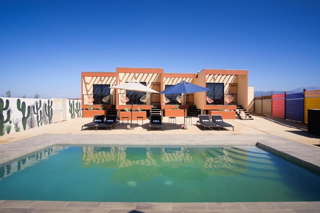 a swimming pool with chairs and umbrellas next to a building at Casas VV in Valle de Guadalupe