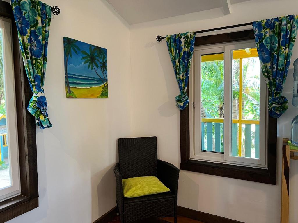 a room with a chair and two windows at Colinda Cabanas in Caye Caulker