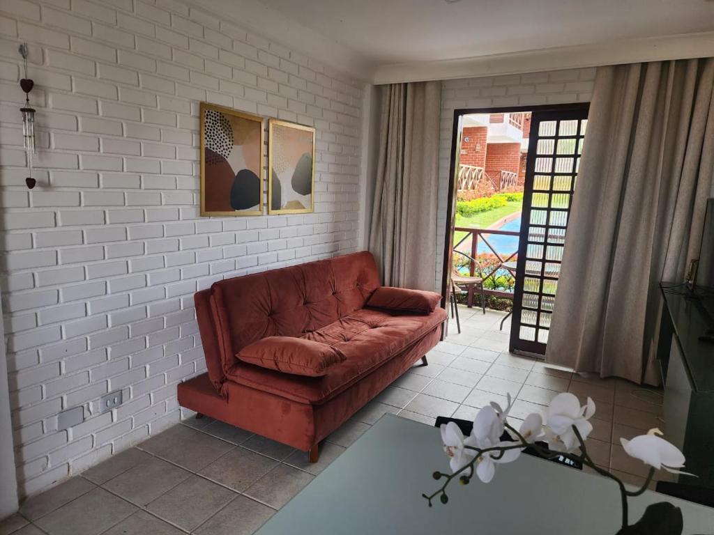 a living room with a red couch and a brick wall at Chalé em Gravatá in Gravatá