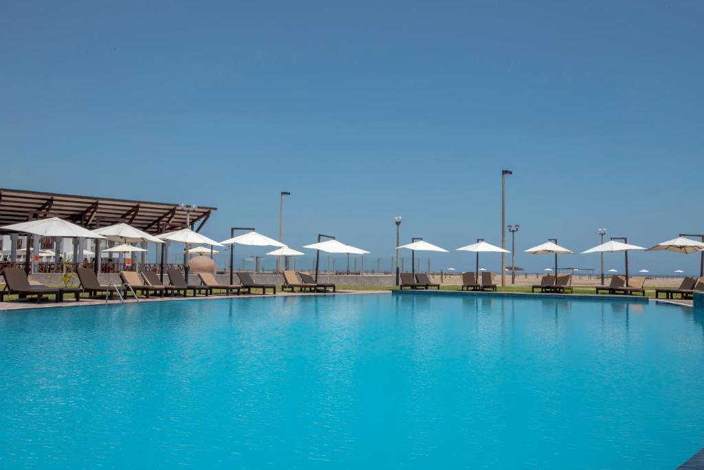 una gran piscina con sillas y sombrillas en DM Hoteles Asia, en Asia