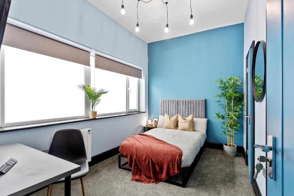 a bedroom with blue walls and a bed with a red blanket at Cozy and Quirky Central Derby Apartments in Derby