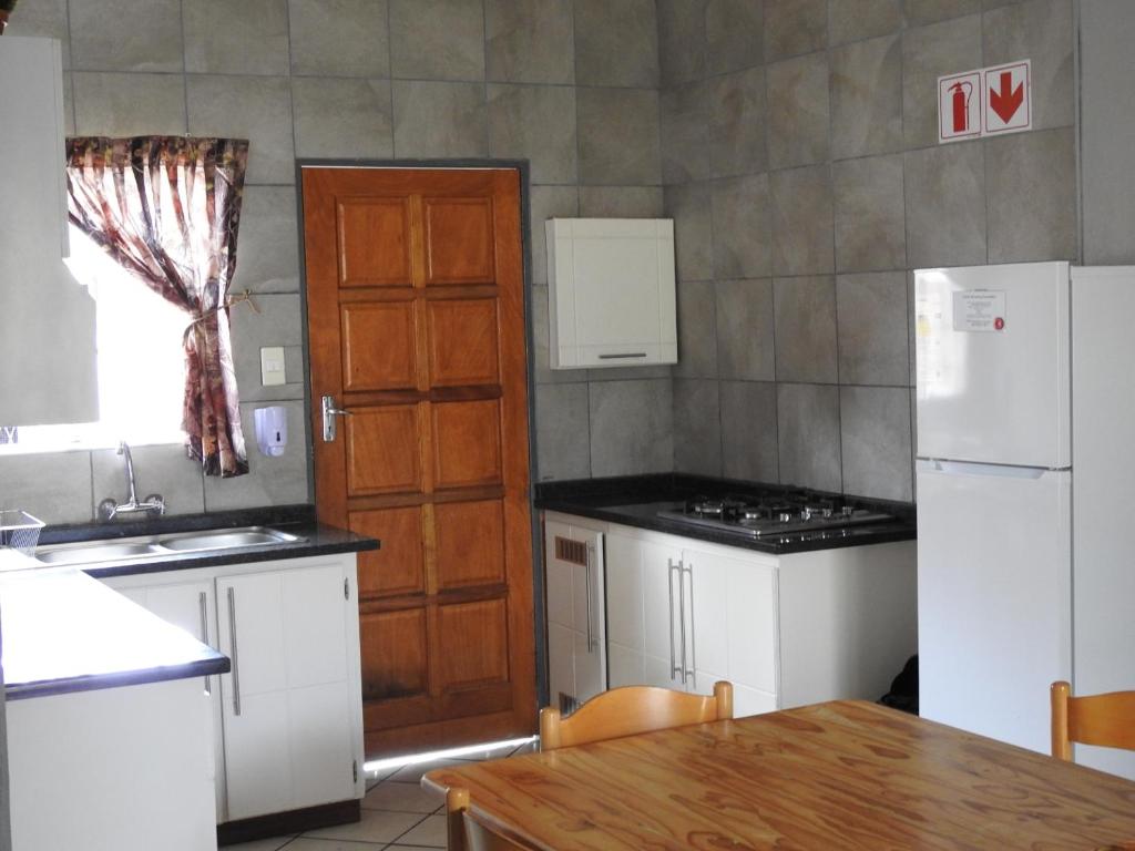 a kitchen with white appliances and a wooden door at ZUCH Accommodation at Pafuri Self Catering - Guest Apartment in Polokwane