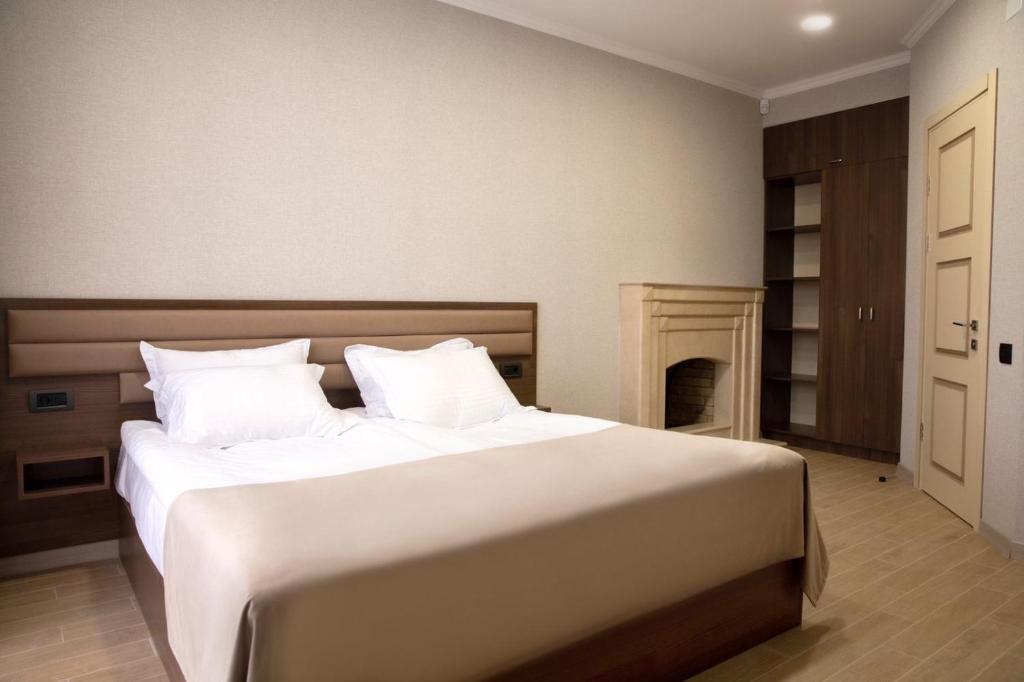 a bedroom with a large white bed and a fireplace at Marrone Hotel Tsaghkadzor in Tsaghkadzor