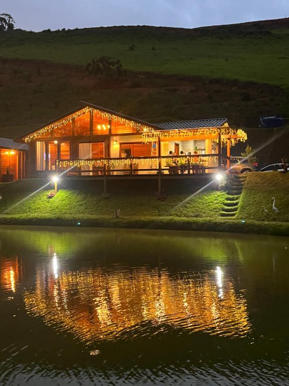 a house on the shore of a lake at night at Rancho Nosso Lago in Domingos Martins