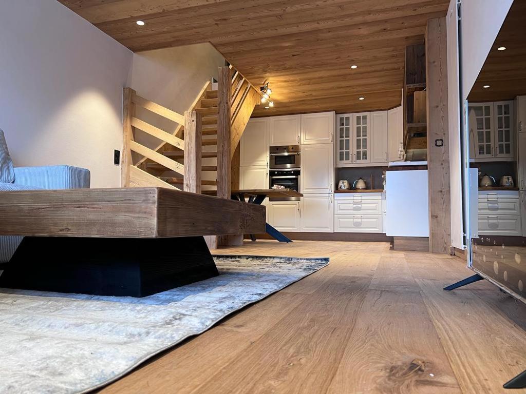 a kitchen and living room with wooden ceilings and a staircase at Cocon au pied des pistes de ski du Mont-d'Arbois in Megève