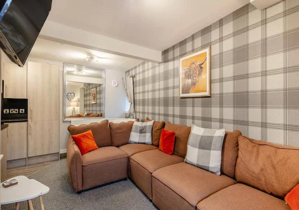 a living room with a brown couch with colorful pillows at Townhouse Apartment 3 Bedroom High St Montrose in Montrose