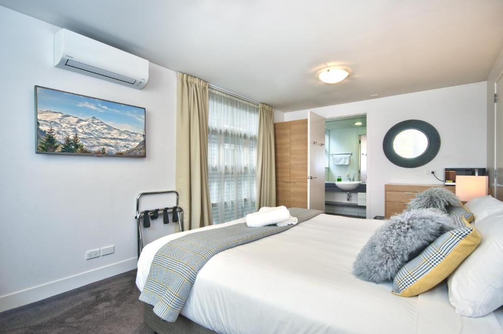 Un dormitorio con una gran cama blanca y una ventana en Lakeshore Studio at the Marina, en Queenstown