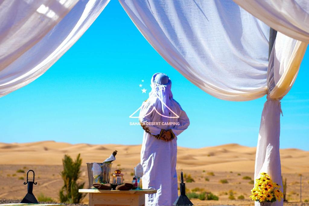 a woman standing under a tent in the desert at Sahara Desert Camping Merzouga & Erg Chebbi Dunes in Erfoud