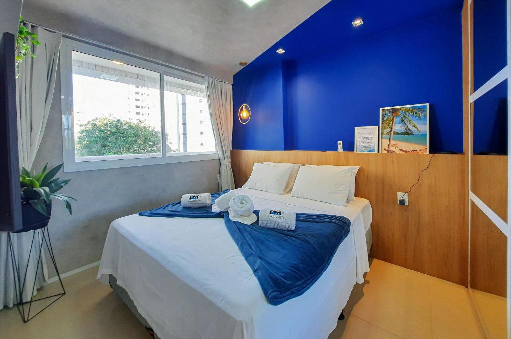a bedroom with a large bed with a blue wall at One Milenio - Luxuoso e Moderno Studio no Cocó in Fortaleza