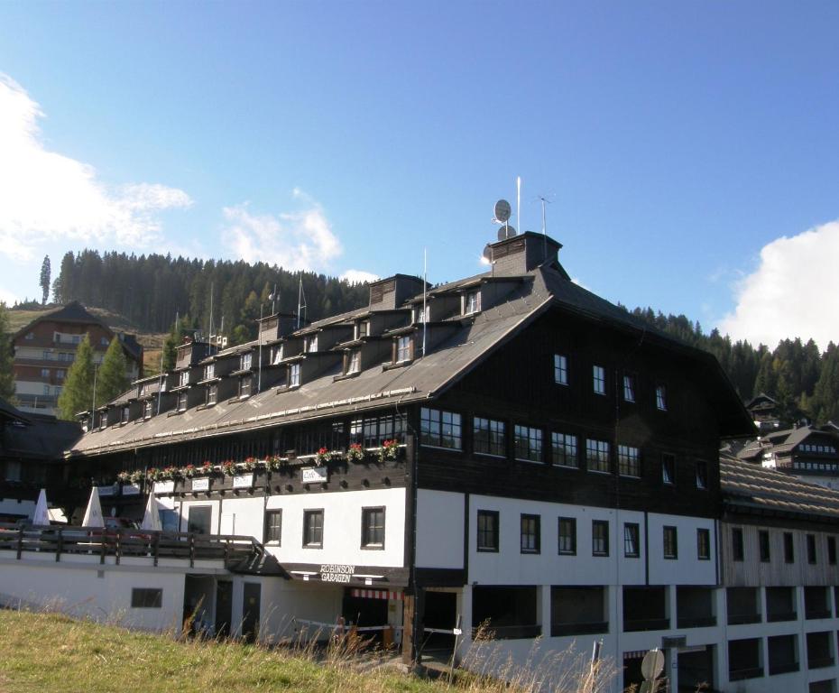 a large white building with a black roof at Alpenhotel Marcius in Sonnenalpe Nassfeld