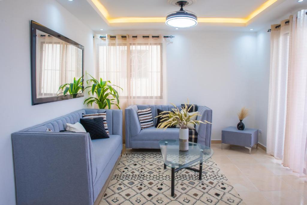 ein Wohnzimmer mit einem blauen Sofa und einem Glastisch in der Unterkunft Luxury, cozy apartment Alma Rosa /15 min airport in Los Tres Ojos de Agua